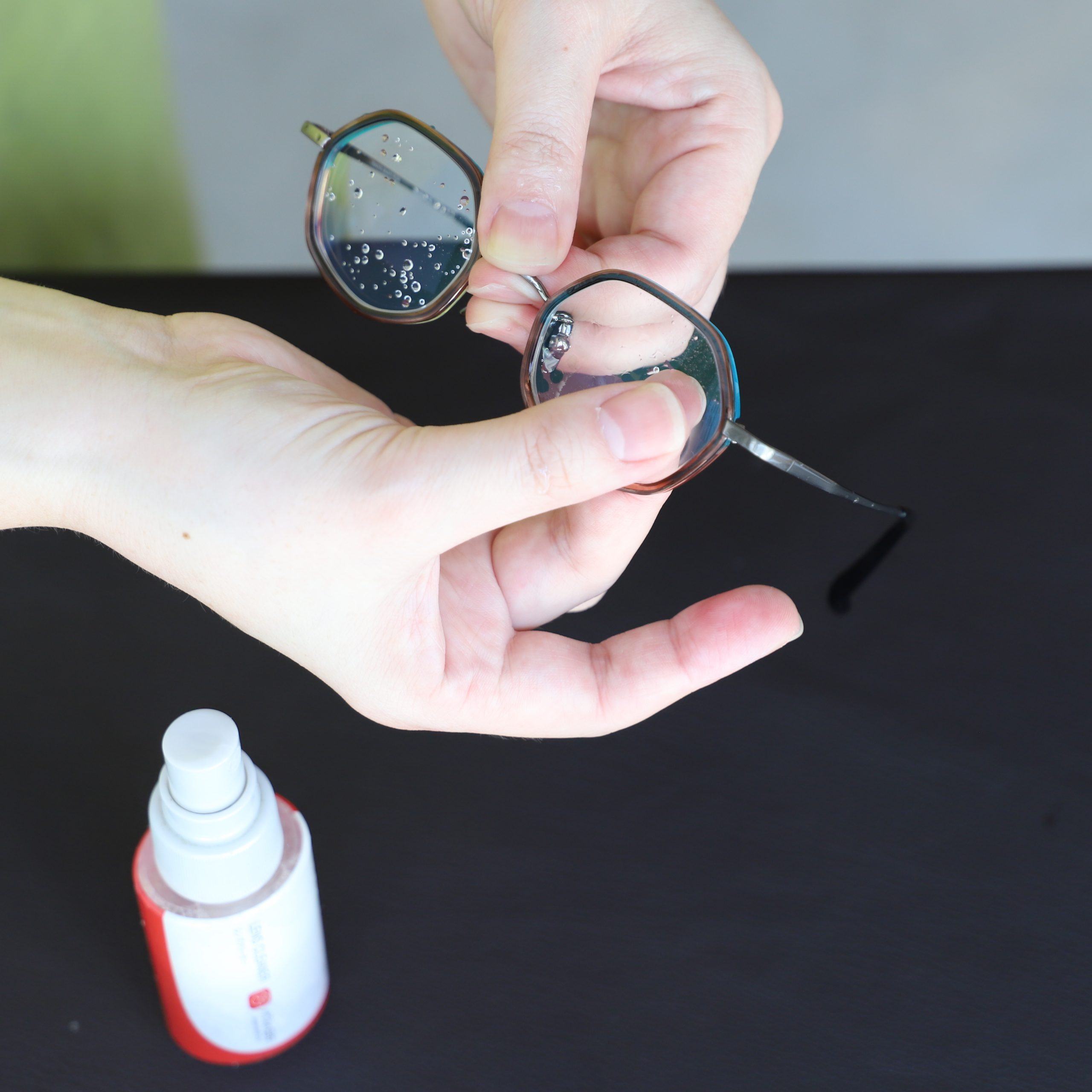 ②メガネクリーナーをレンズに吹きかけ、汚れを浮かすように指で軽くなじませます。
